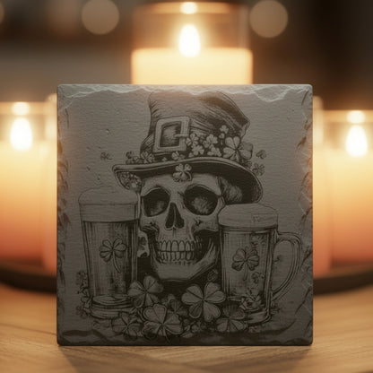 Decorative slate engraved coaster with skull and shamrock design in front of lit candles