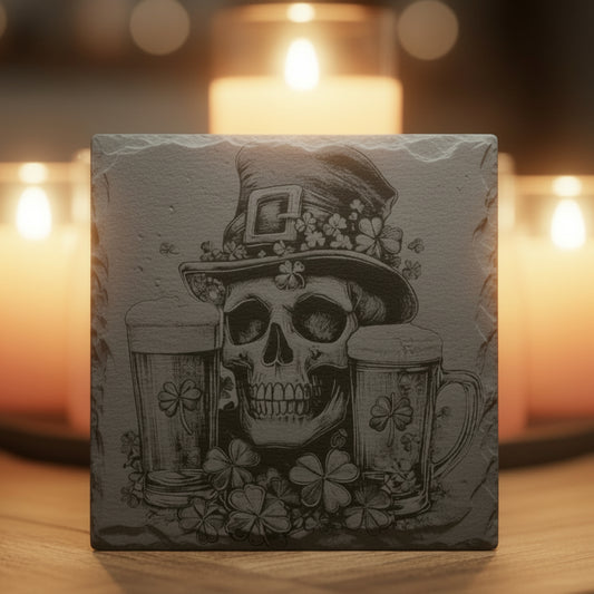 Decorative slate engraved coaster with skull and shamrock design in front of lit candles