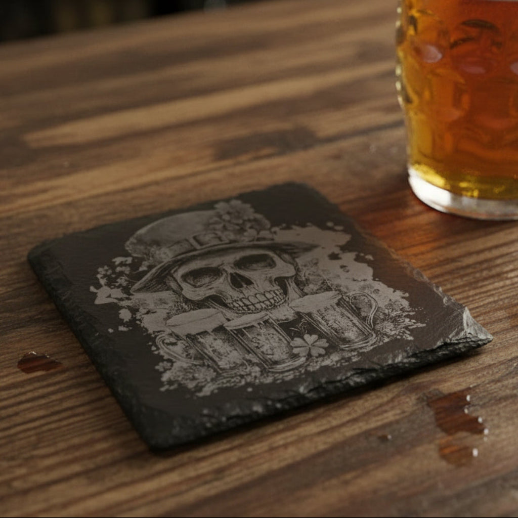 Slate coaster with a skull wearing a hat and holding beer mugs design, placed on a woven surface.