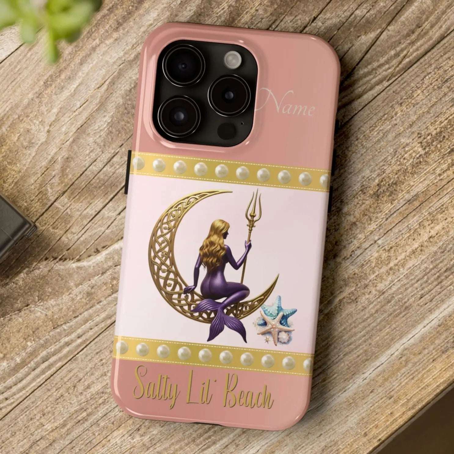 Pink and White 15 Pro iPhone Case with mermaid sitting on a celtic crescent moon holding a trident that says Salty Lil' Beach. Personalized with name.