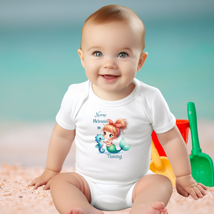 White baby bodysuit with short-sleeves with mermaid and seahorse that says Mermaid in Training with space for a name above.