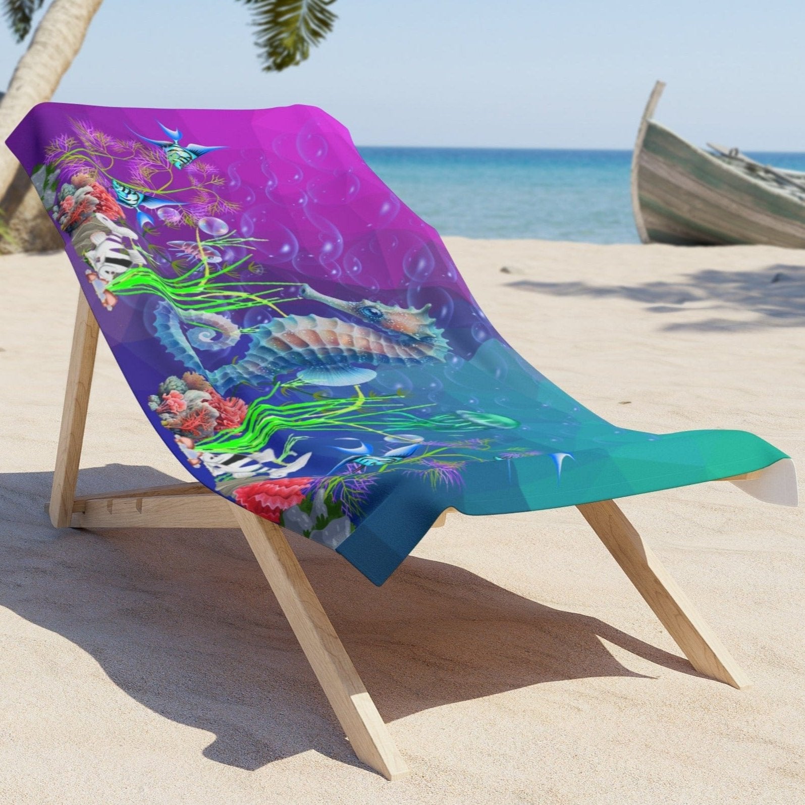 Purple to aqua gradient beach towel with Sea horse and underwater plants laying on lounge chair