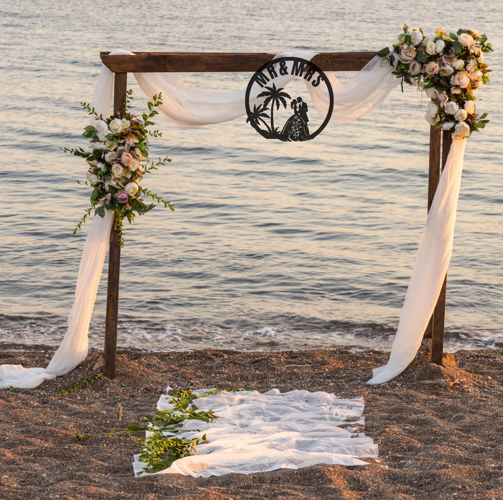 a black round metal sign with Mr. & Mrs. and a wedding couple hanging from a trellis for a wedding