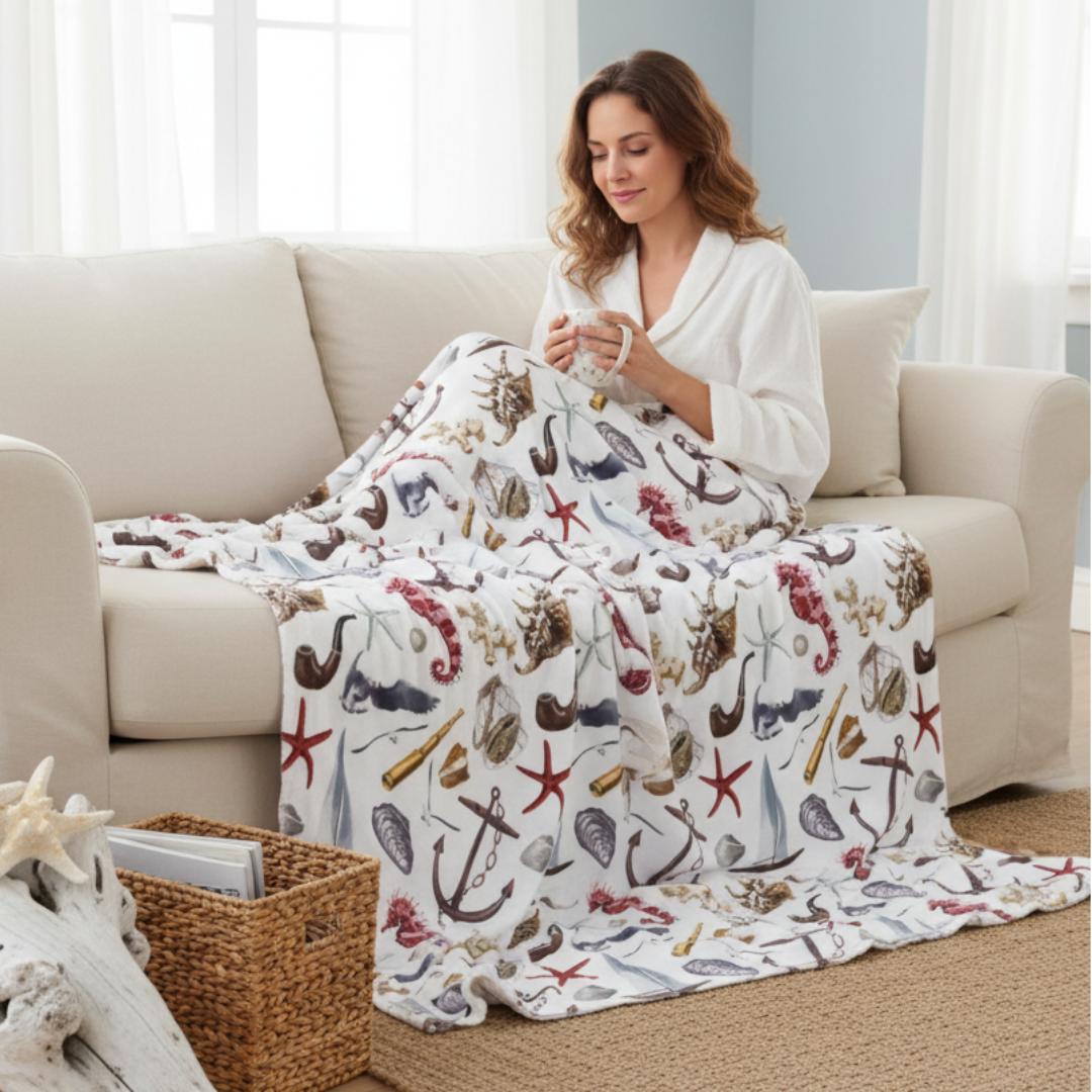 Woman sitting on a couch with a nautical-themed blanket, surrounded by coastal decor.