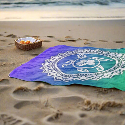 Beach blanket with mandala sea turtle on purple and green gradient background.
