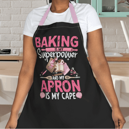 Person wearing a black apron with baking elements and text 'Backing is my Superpower and my Apron is my cape.