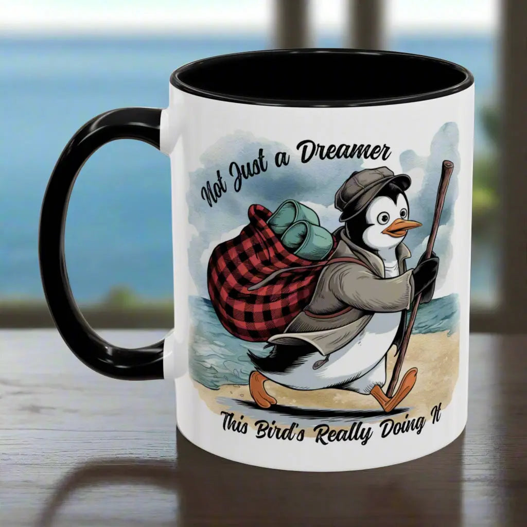 White 11 oz coffee mug with a black interior and handle featuring a fun beach design of a penguin running away on the sand with the text 'Not Just a Dreamer, This Bird’s Really Doing It.' A playful and unique gift for beach lovers and dreamers.