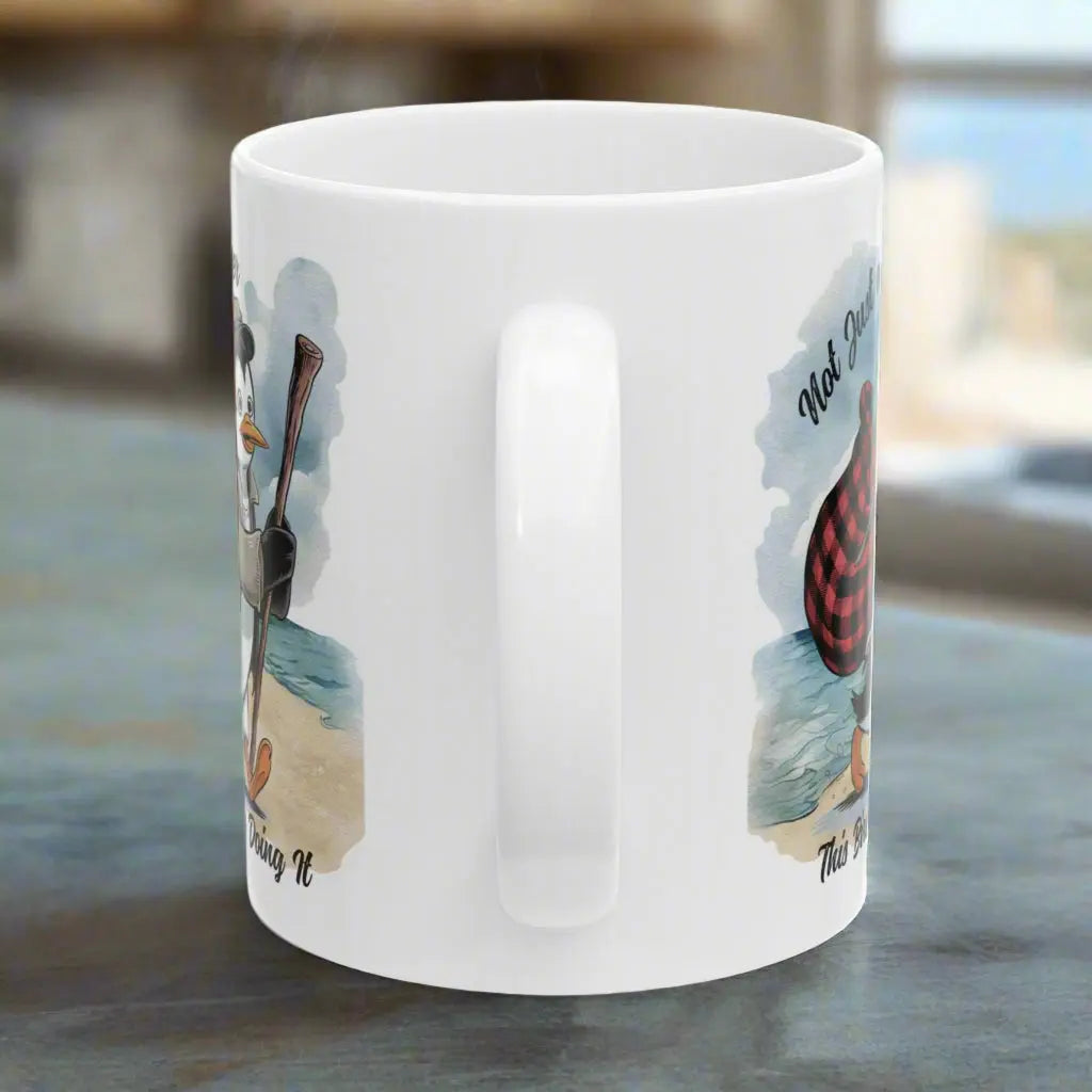 Side view of White 11 oz coffee mug featuring a fun beach design of a penguin running away on the sand with the text 'Not Just a Dreamer, This Bird’s Really Doing It.' A playful and unique gift for beach lovers and dreamers.