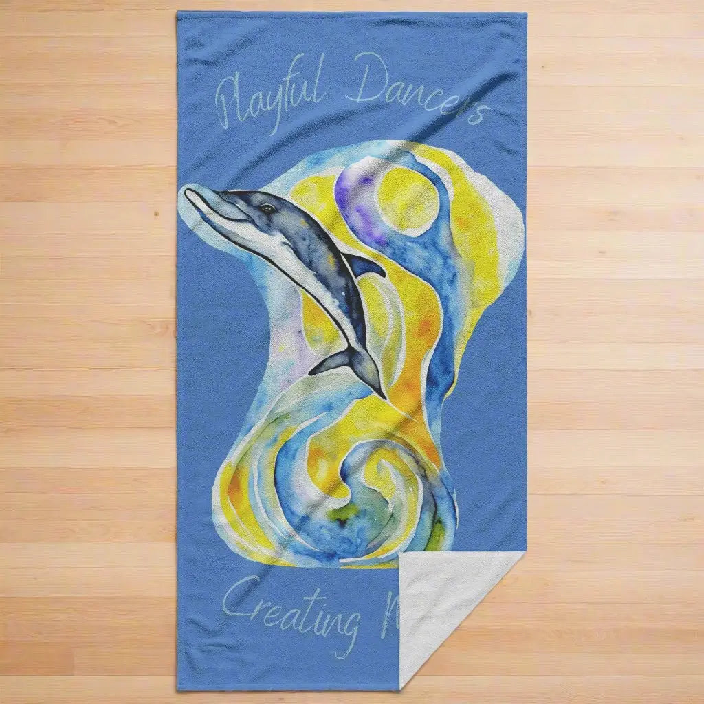 Blue beach towel with abstract dolphin image with yellow and blue background with the phrase Playful Dancers Creating Magic.