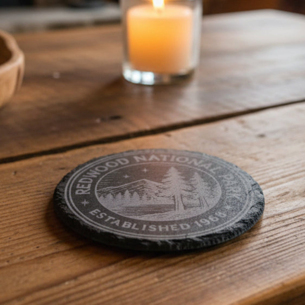 Black 4" round engraved slate coaster with Redwood National Park patch with scenic design and text.