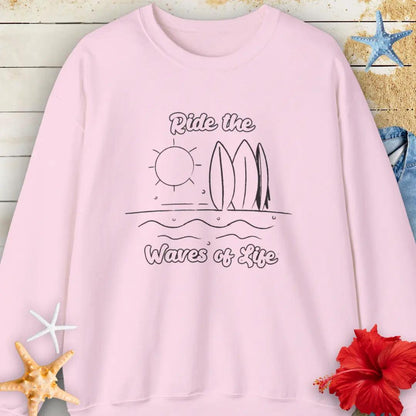 Our Ride the Waves of Life Sweatshirt  in Light Pink with Surfboards and the sun line art with the phrase ide the Waves of Life. Perfect for any surfing enthusiast.