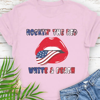 Light Pink T-shirt with rolling stones lips with American flag tongue hanging out that says Rockin' the Red, White & Beach with text that is filled with the flag.