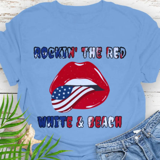 Carolina Blue T-shirt with rolling stones lips with American flag tongue hanging out that says Rockin' the Red, White & Beach with text that is filled with the flag.