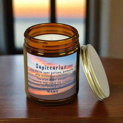Elegant Sagittarius Zodiac hand-poured coconut apricot wax scented candle in a 9 oz amber glass jar with gold lid, featuring a picture of the ocean at sunset with a sailboat in the distance and an inspirational quote personalized. A beach-inspired astrology gift, perfect for relaxation and decor.
