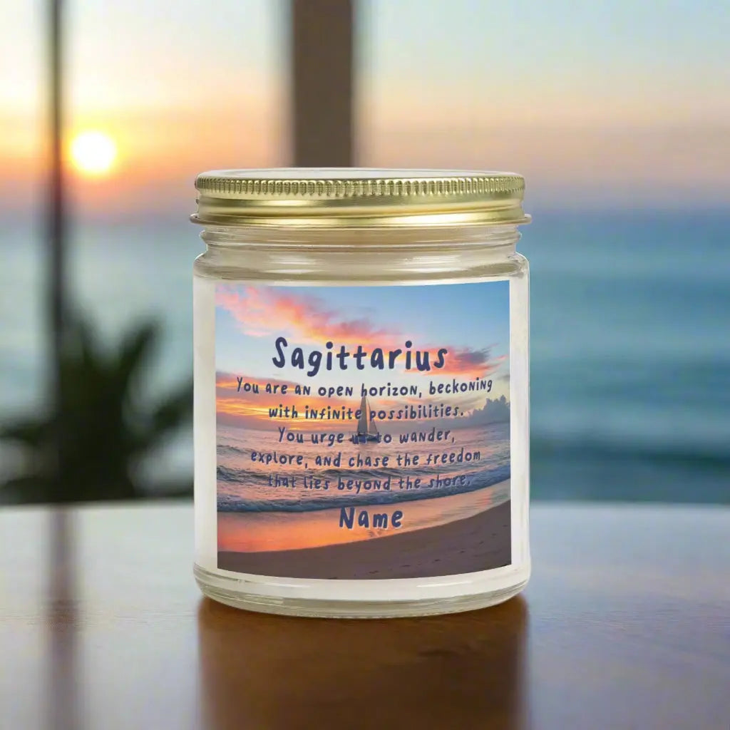 Elegant Sagittarius Zodiac hand-poured coconut apricot wax scented candle in a 9 oz clear glass jar with gold lid, featuring a picture of the ocean at sunset with a sailboat in the distance and an inspirational quote personalized. A beach-inspired astrology gift, perfect for relaxation and decor.