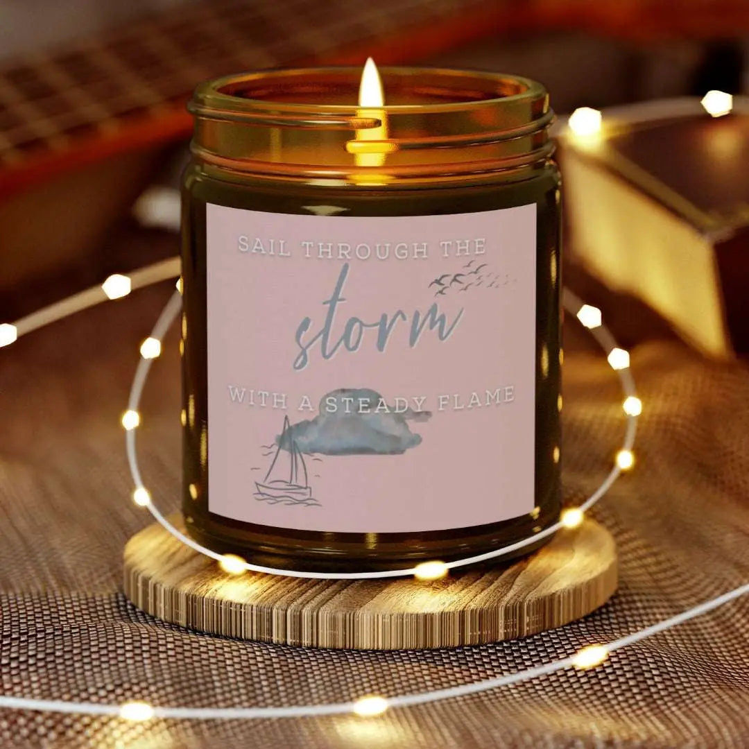 Amber 9 oz Jar Beachwood candle featuring label with a sailboat design and the inspirational phrase 'Sail Through the Storm with a Steady Flame,' making it the perfect addition to any nautical or coastal-themed home decor.