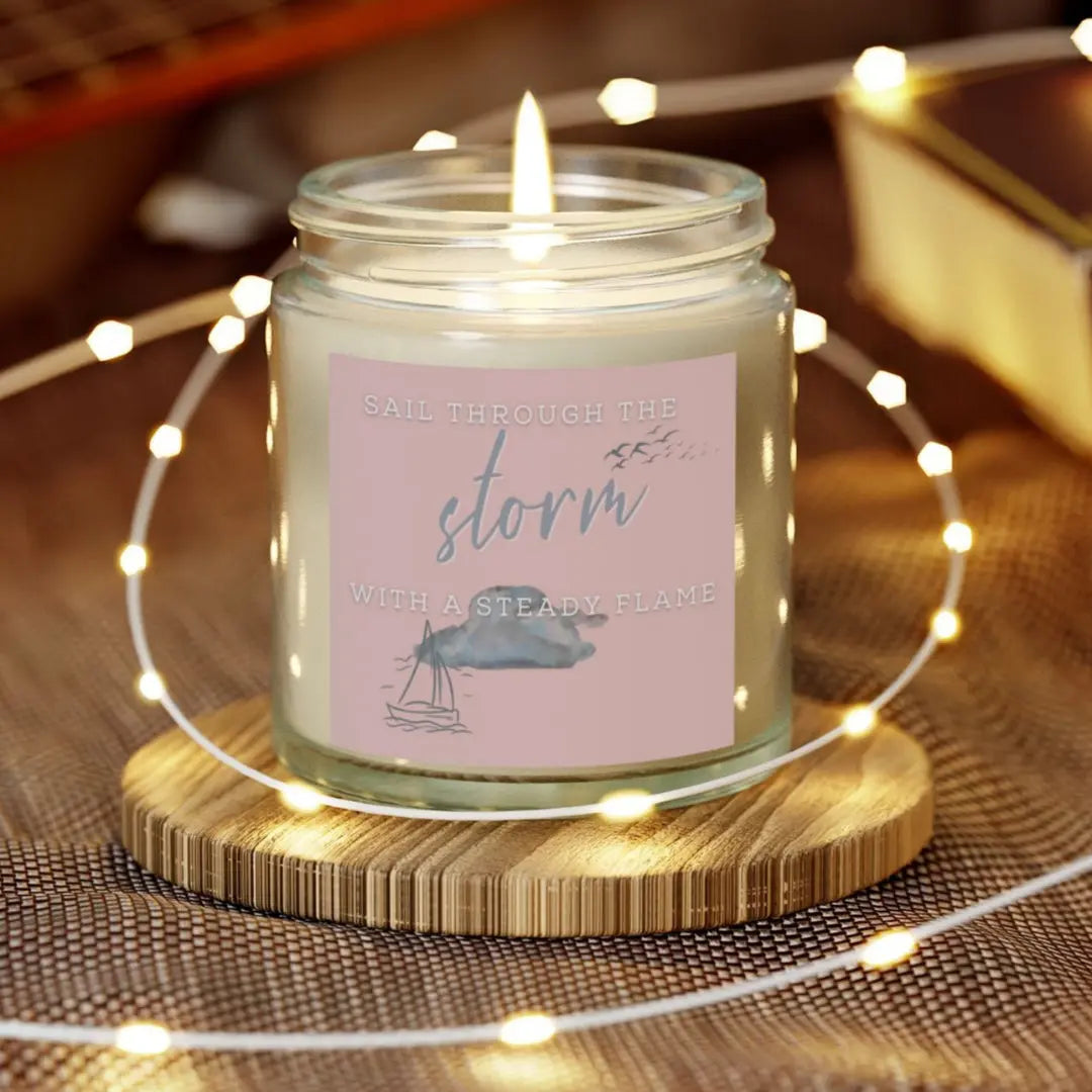 Clear scented 4 oz candle with label featuring a sailboat design and the inspirational phrase 'Sail Through the Storm with a Steady Flame,' making it the perfect addition to any nautical or coastal-themed home decor.