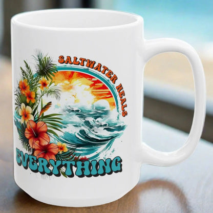 White ceramic 15 oz mug that says Saltwater Heals Everything around ocean waves with tropical flowers
