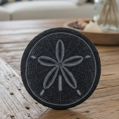 Black slate coaster with sand dollar design engraved.