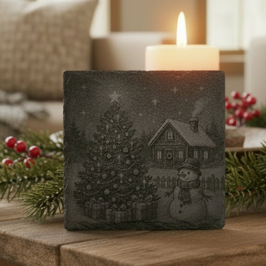 Decorative slate coaster engraved with a snowy Christmas scene featuring a tree and snowman.