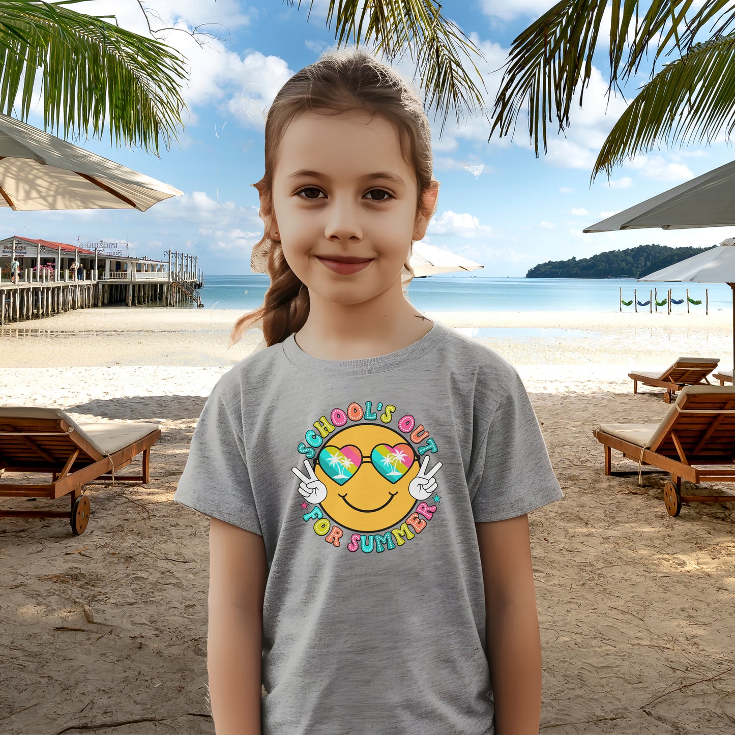 Child in grey t-shirt with a beach themed smiley face that says Schools Out for Summer