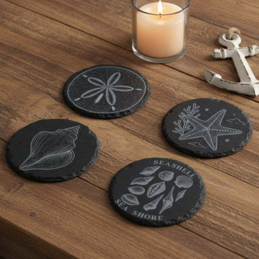 Four black slate coasters with engraved sea-themed designs.