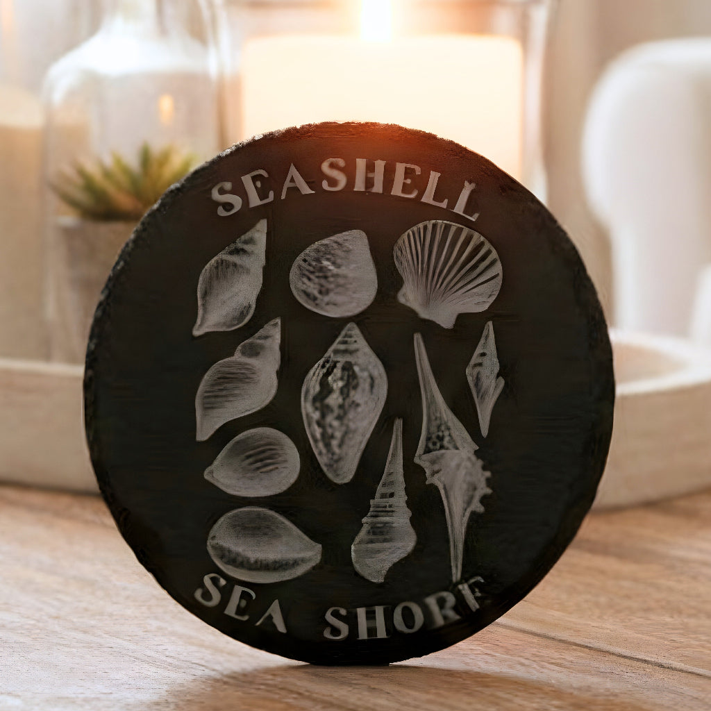 Black slate coaster with white shell illustrations and 'Seashell Sea Shore' text engraved.