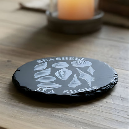 Black coaster with white shell design and 'Seashell Sea Shores' text engraved.