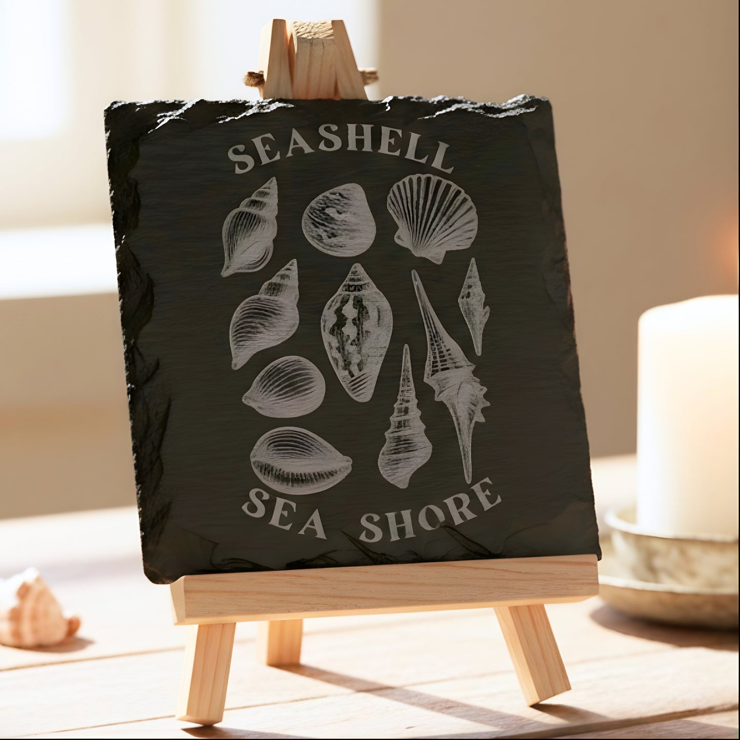 Black slate coaster with white shell illustrations and 'Seashell Sea Shore' text engraved.