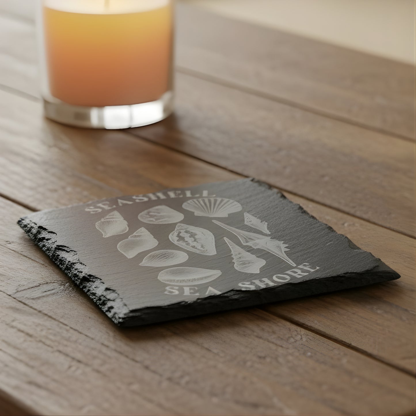 Black slate coaster with white shell illustrations and 'Seashell Sea Shore' text engraved.