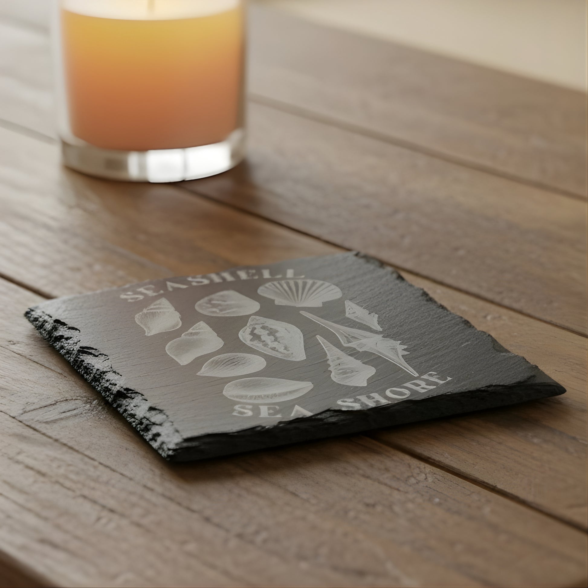 Black slate coaster with white shell illustrations and 'Seashell Sea Shore' text engraved.