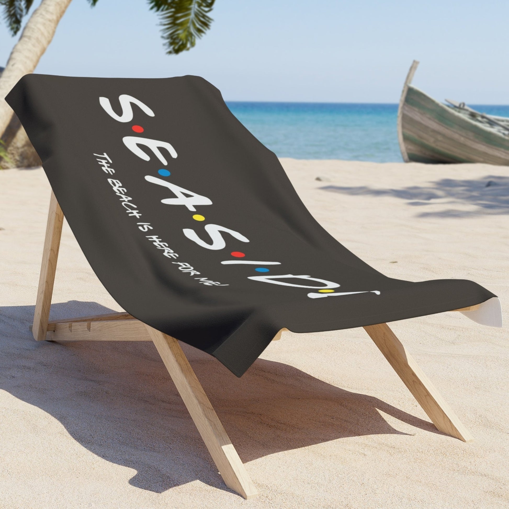 Black beach towel that says Seaside with colored dots in between and says The Beach is Here for Me laying on chair