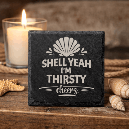 Square black slate coaster engraved “Shell Yeah I’m Thirsty cheers” with seashell icon.