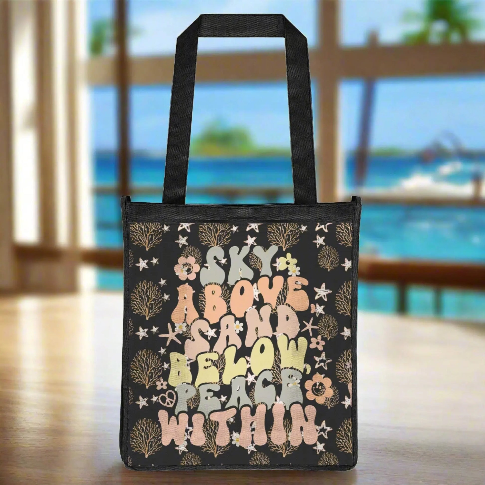 Black grocery bag with ocean foliage and starfish in tan colors with retro text that says sky above sand below peace within