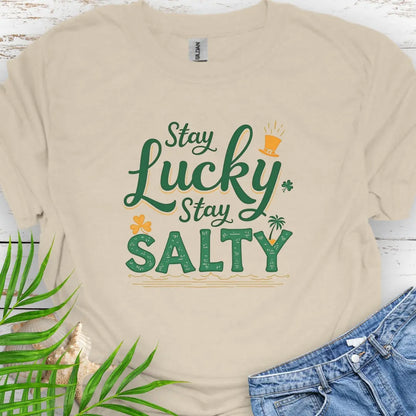 Our Stay Lucky Stay Salty Natural T-shirt with St. Patrick's Day and beach embellishments including shamrock, leprechaun hat, palm tree and ocean waves.