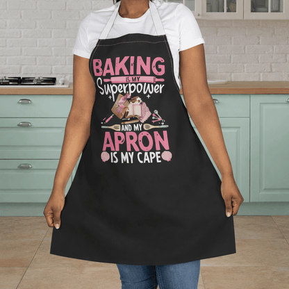 Person wearing a black apron with baking elements and text 'Backing is my Superpower and my Apron is my cape.