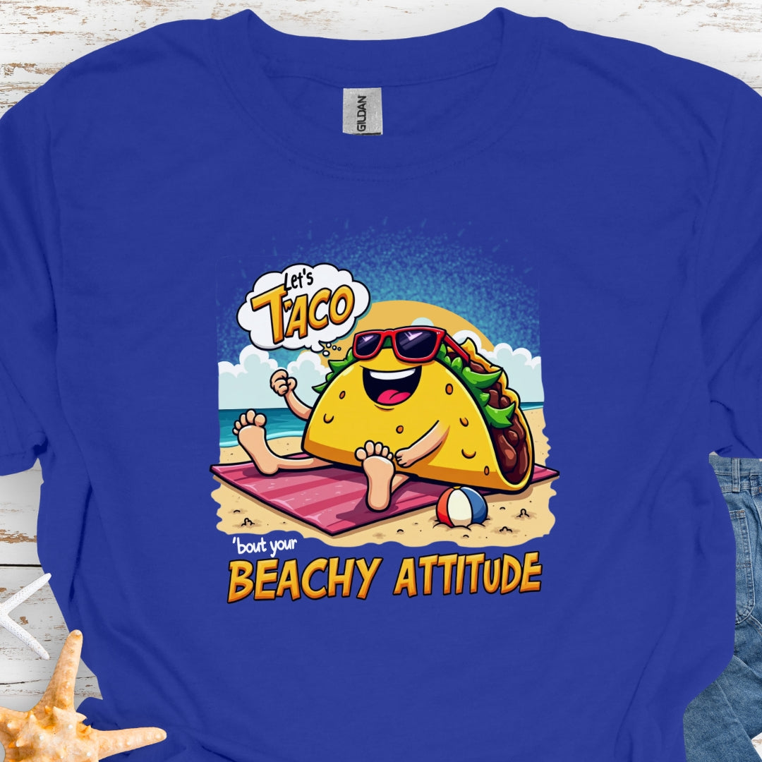 Royal Blue t-shirt with a taco wearing sunglasses laying on a beach towel on the beach with the text Let's Taco 'bout your Beachy Attitude.