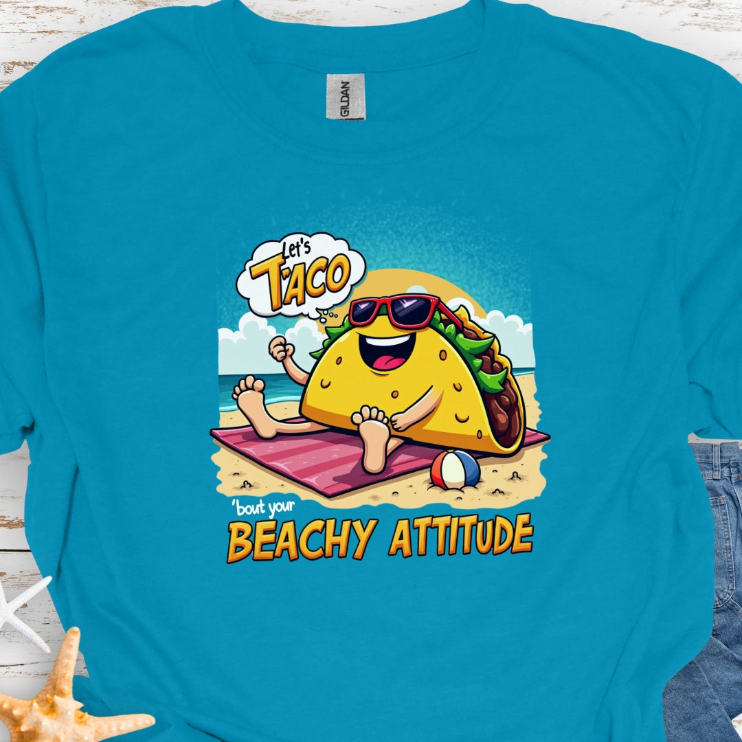 Tropical Blue  t-shirt with a taco wearing sunglasses laying on a beach towel on the beach with the text Let's Taco 'bout your Beachy Attitude.