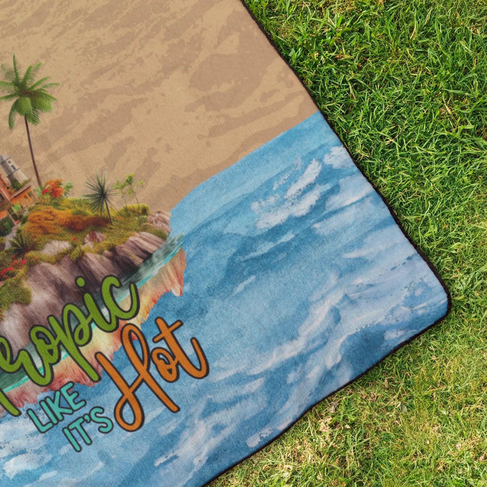 Corner of Outdoor beach blanket with sand on top half, water on bottom half with flamingo on island in middle with text Tropic like It's Hot.