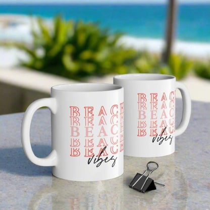 Two white 11 oz. mugs with Beach repeated and vibes on the bottom