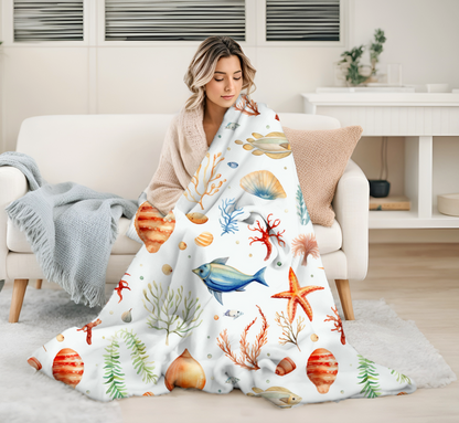 White blanket with fish, starfish, seashells and underwater plant life.