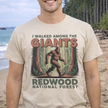 Person wearing a t-shirt with a Bigfoot graphic and text about Redwood National Forest on a beach.