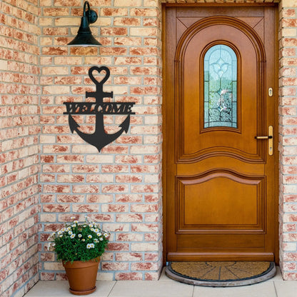 Black metal wall art shaped like an anchor with a heart at the top and the word “Welcome” cut out in the center; made of powder-coated steel hanging near the front door.