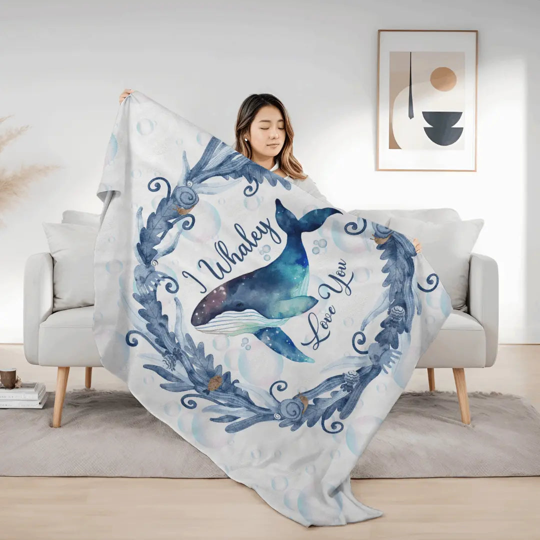 White Velveteen Plush blanket with blue marine plant wreath with swimming whale in the middle and text I Whaley Love You -perfect for snuggling up with your beachy loved ones!