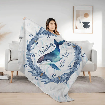 White Velveteen Plush blanket with blue marine plant wreath with swimming whale in the middle and text I Whaley Love You -perfect for snuggling up with your beachy loved ones!