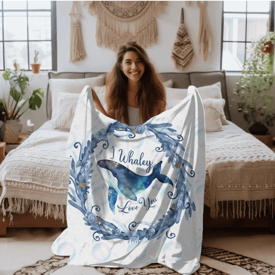 White Velveteen Plush blanket with blue marine plant wreath with swimming whale in the middle and text I Whaley Love You -perfect for snuggling up with your beachy loved ones!
