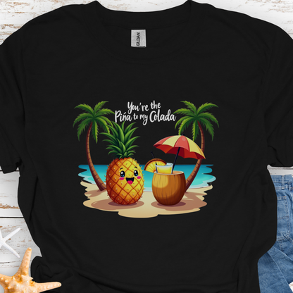 Black T-shirt with a pineapple and a coconut pina colada on a beach between two palm trees with the text You're the Pina to my Colada.