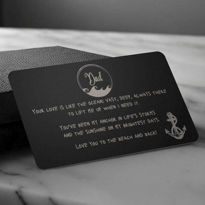 A black wallet sized stainless steel card that has a wave circle around the text dad and then says "your love is like the ocean; vast, deep, always there to lift me up when I need it. You've been my anchor in life's storms and the sunshine on my brightest days. Love you to the beach and back" and an image of an anchor on the bottom right side.