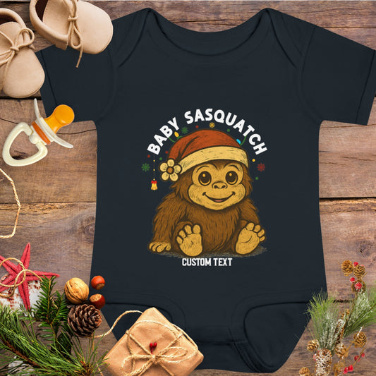Black baby onesie with a cartoon Sasquatch wearing a Santa hat custom text.
