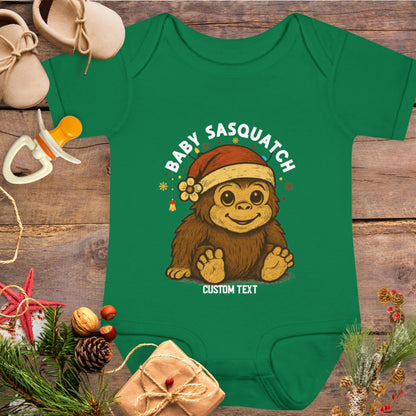 Green baby onesie with a cartoon Sasquatch wearing a Santa hat and custom text.
